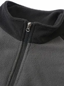 Primer plano de una sudadera de forro polar gris y negra con cuello alto y detalle de cremallera.