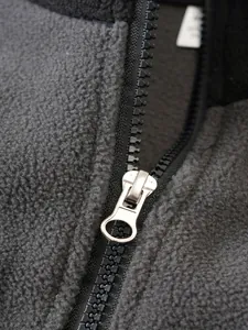 Detalle macro de la cremallera metálica y la textura del tejido polar gris de la sudadera.