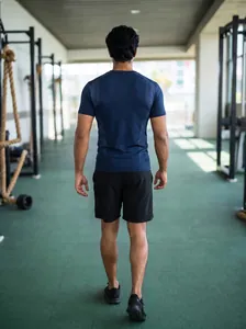 Back view of a men's navy blue breathable athletic t-shirt shown in a gym setting