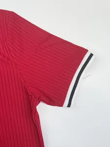 Close-up detail of a red ribbed athletic t-shirt sleeve with black and white striped cuff