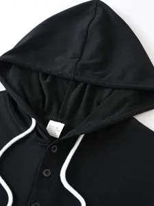 Close-up detail of a black men's hoodie featuring white drawstrings and buttons