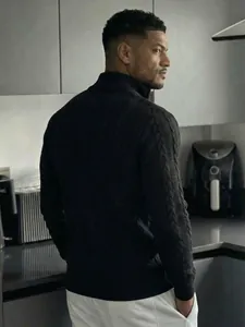 Vista posteriore di un maglione nero a dolcevita da uomo con motivi a treccia jacquard