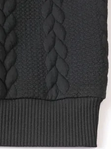 Dettaglio della trama a trecce nere e del polsino a coste di un maglione da uomo