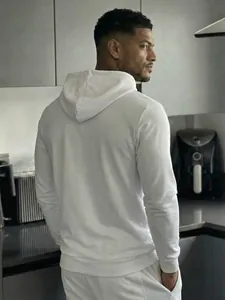 Back view of a white casual men's long-sleeved hoodie in a modern kitchen setting