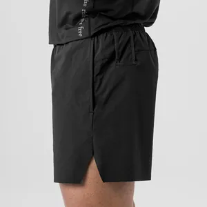 Side view detail of black quick-dry men's athletic shorts showing mesh vents and side slit.