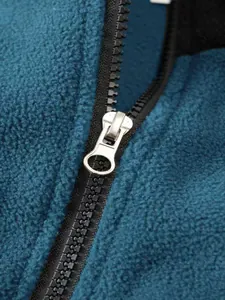 Primer plano de una cremallera metálica en un jersey de forro polar azul petróleo