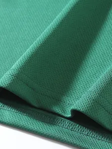Close-up of green breathable mesh fabric and high-quality stitching on a sports top.