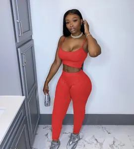 Full body detail shot of a woman wearing a red cami top and high waisted leggings.