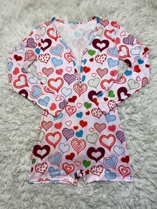 Detailed view of pink long sleeve romper with colorful heart prints on white shaggy rug