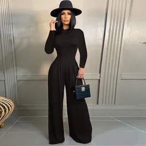Full length view of a model wearing a black jumpsuit set with a hat in a studio setting