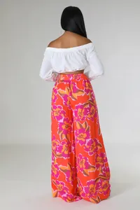 Rückansicht eines Modells in weißem Crop-Top und weit geschnittener Hose mit Blumenmuster