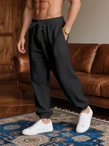 Men's lightweight black jogger pants styled with white sneakers in a home interior