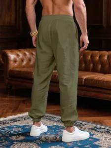Back view of men's loose olive green breathable joggers in a luxury room setting