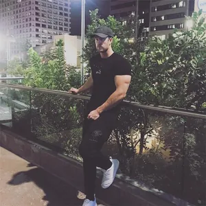 Detail view of a man wearing a black slim-fit gym t-shirt in an outdoor night setting