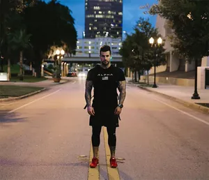 Man in black ALPHA sports T-shirt standing on urban street at dusk for fitness training