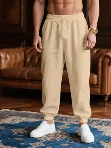 Detail view of men's lightweight beige joggers with elastic drawstring waist and cuffed ankles.