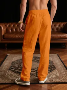Rückansicht einer locker sitzenden orangefarbenen Freizeithose für Herren im gemütlichen Wohnzimmer