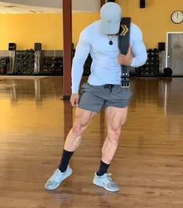 Atleta professionista con una maglia grigia aderente a maniche lunghe in una palestra