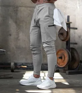 Detailed view of men's grey fitness cargo joggers with multi-pockets in gym setting