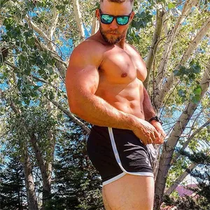 Modelo masculino musculoso con pantalones cortos de malla negra transpirable al aire libre