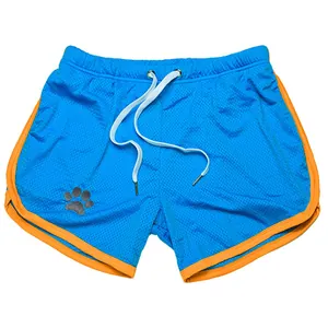 Detalle de pantalones cortos deportivos de malla azul con ribete naranja y logo de pata