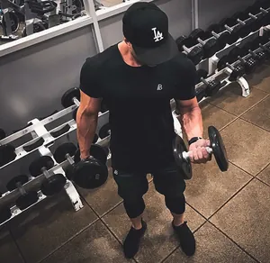 Muscular fitness man in black gym outfit lifting dumbbells in gym environment