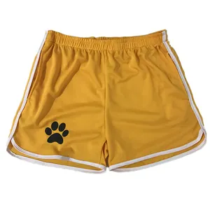 Primer plano de pantalones cortos deportivos de malla amarilla con huella negra.