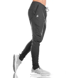 Close-up profile of men's slim-fit charcoal grey joggers with zippered ankles and logo detail.