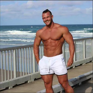 Muskulöses männliches Model in weißen, schnell trocknenden Mesh-Strandshorts am Strand
