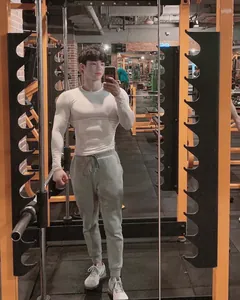 Mann trägt weißes Kompressions-Langarmshirt im Fitnessstudio-Selfie für das Training