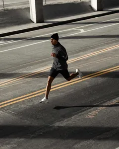 Atleta masculino corriendo en la calle con pantalones cortos deportivos de doble capa