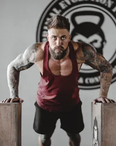 Detailed view of men's athletic maroon tank top during an intense gym workout session