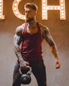 Detailed view of burgundy muscle fitness tank top on a tattooed model during workout