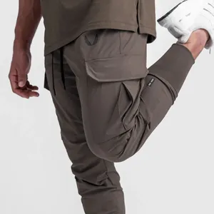Detail shot of brown slim fit cargo joggers for men showing pocket and athletic wing logo