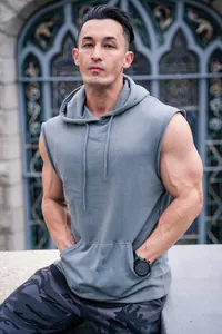 Close-up of a grey sleeveless gym hoodie worn by a muscular male model outdoors