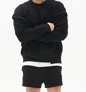 Detalle del ajuste de una sudadera negra minimalista de cuello redondo extragrande.