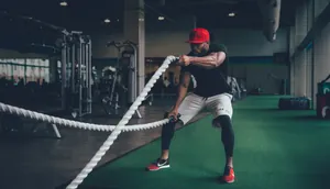 Action shot of men's athletic slim fit t-shirt during gym battle rope training