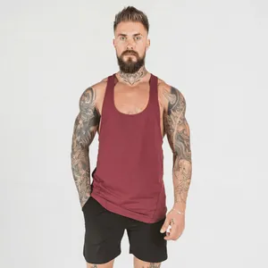 Front view of a muscular tattooed man wearing a burgundy fitness stringer tank top.
