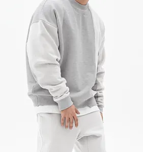 Detalle de sudadera oversize gris claro con diseño de bloques de color y hombros caídos