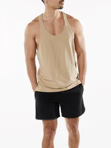 Homme musclé en débardeur de sport kaki et short noir dans un studio de photo.