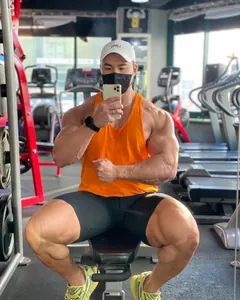 Detalle de camiseta de tirantes naranja en un modelo musculoso en el gimnasio