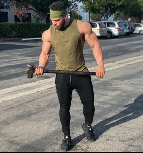 Hombre atlético con camiseta de gimnasia verde oliva entrenando con un mazo de hierro