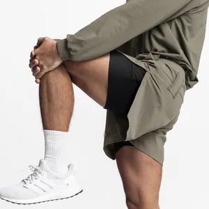 Close-up of olive green athletic shorts with black compression liner on model