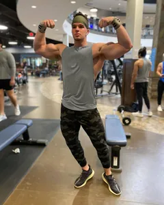 Camiseta de tirantes gris de fitness para hombre que muestra un ajuste atlético en el gimnasio