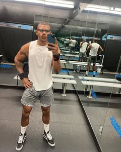 Modelo de fitness con una camiseta de tirantes blanca en un gimnasio profesional