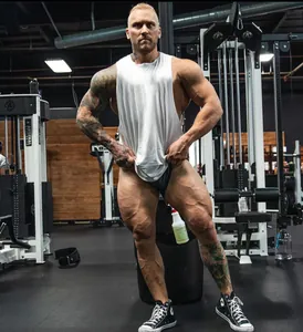 Hombre musculoso con camiseta de tirantes blanca de algodón transpirable en un gimnasio pro