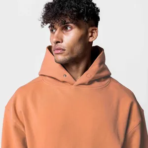 Détail du col à capuche avec bouton-pression sur un sweat à capuche en coton orange