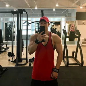 Rood ademend katoenen fitness tanktop voor heren getoond in een sportschool omgeving