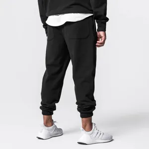 Rear view of black men's jogger pants featuring elastic cuffs and white sneakers.