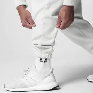 Close-up of white loose fitness sweatpants with elastic cuffs and sneakers
